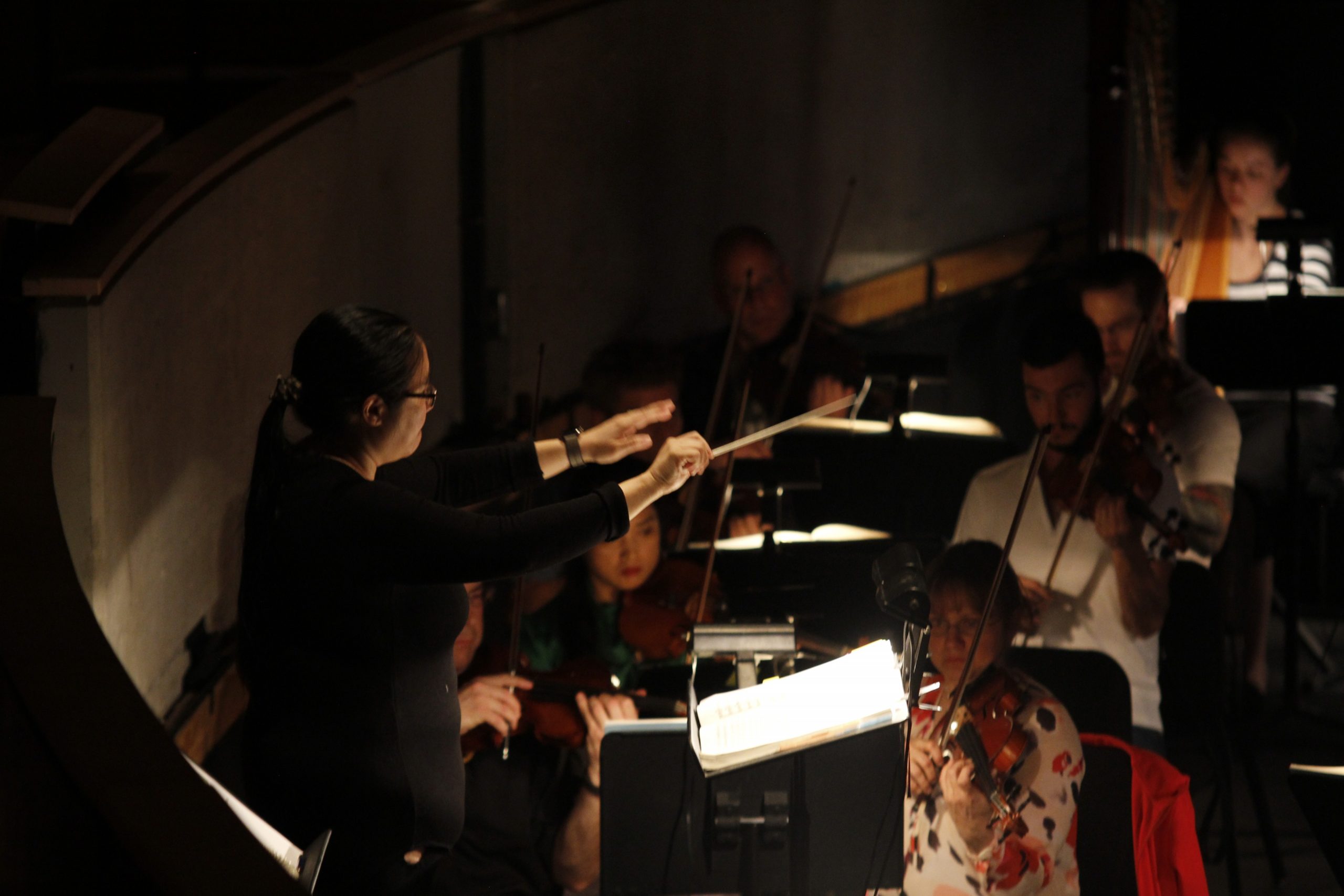 Women in Musical Leadership's Conductor Jennifer Tung leads her orchestra in a song.